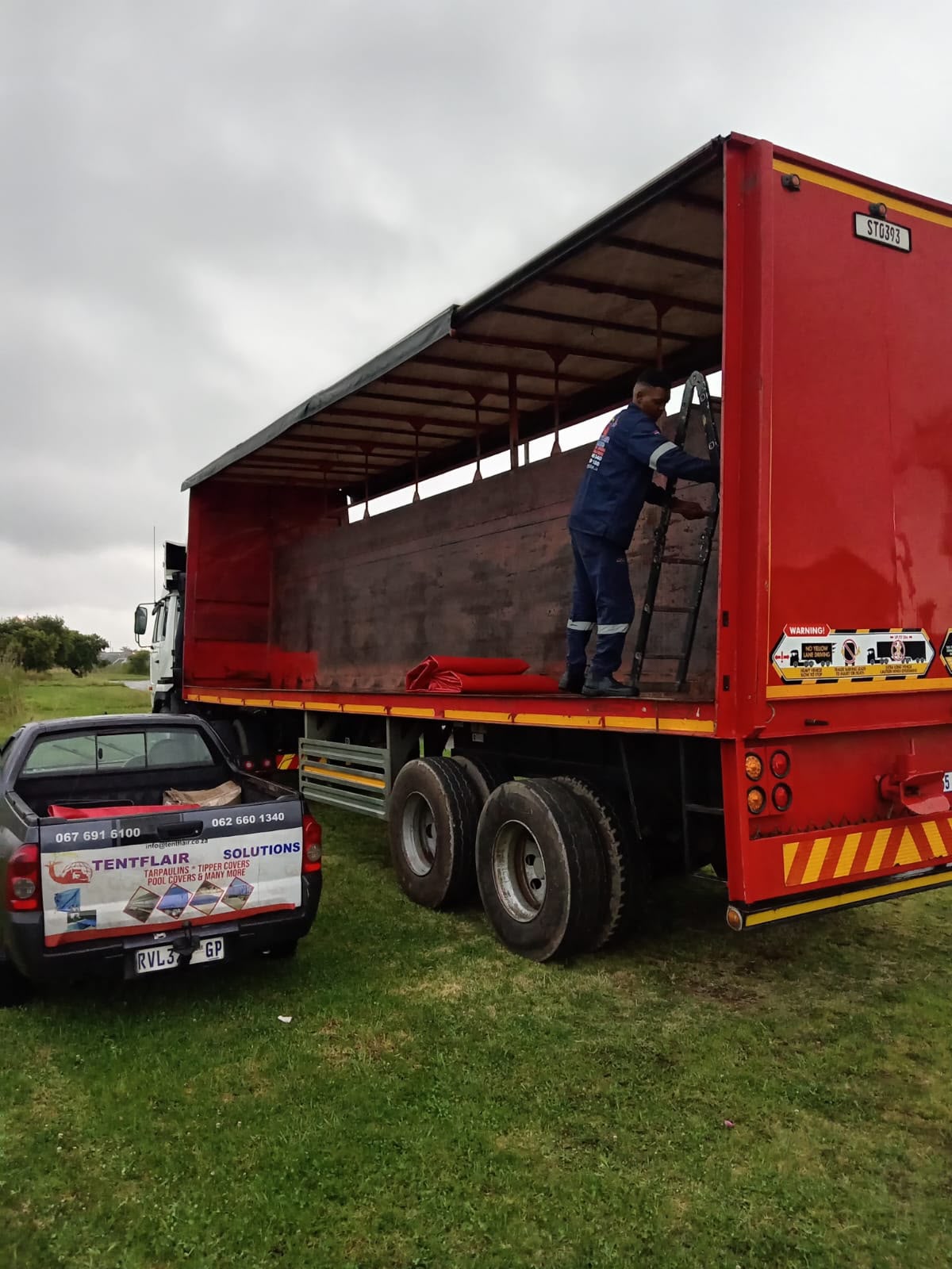 Tunnel Fox team fitting a truck curtain to a red curtain-side trailer