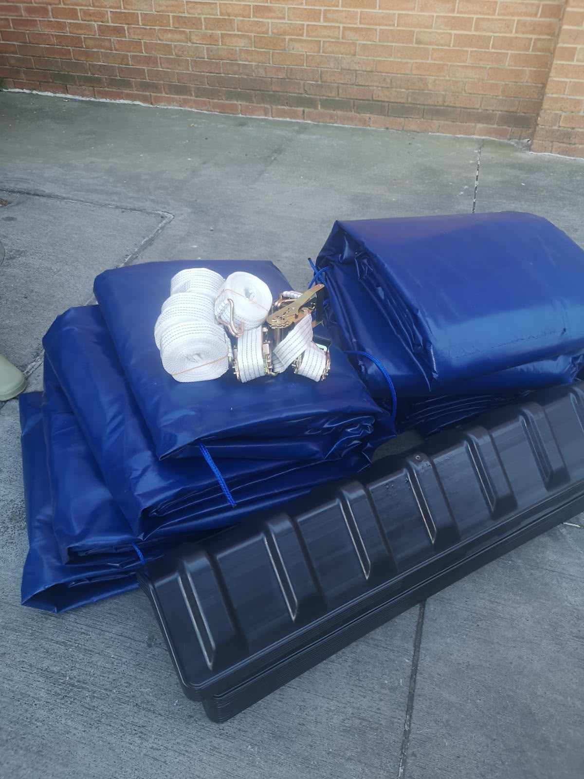 Folded PVC tarpaulins with ratchet straps and rope ready for dispatch